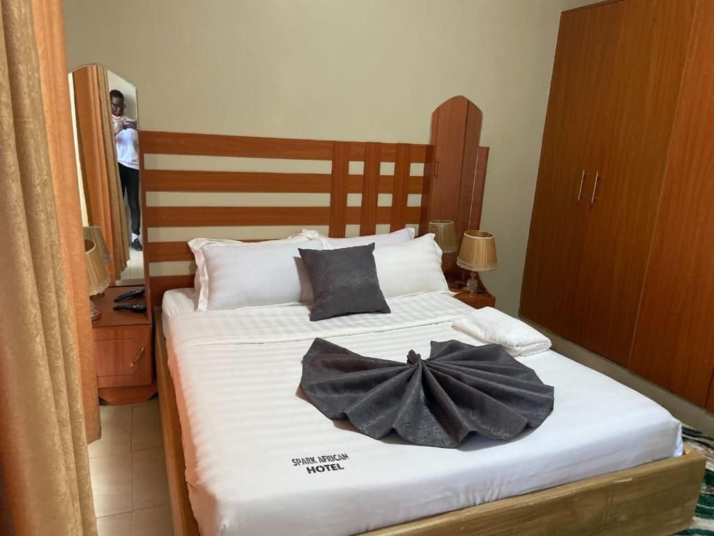 Una habitación de hotel con un marco de cama de madera, una mesita de noche, una lámpara y un armario.