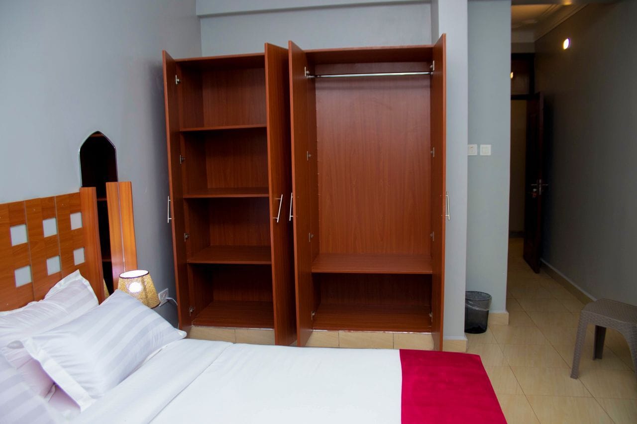 A bedroom with a bed, a wardrobe, and a nightstand.
