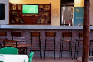 A bar area with a television, shelves with bottles, and a refrigerator. - Spark Africa Hotel Jinja (Jinja)