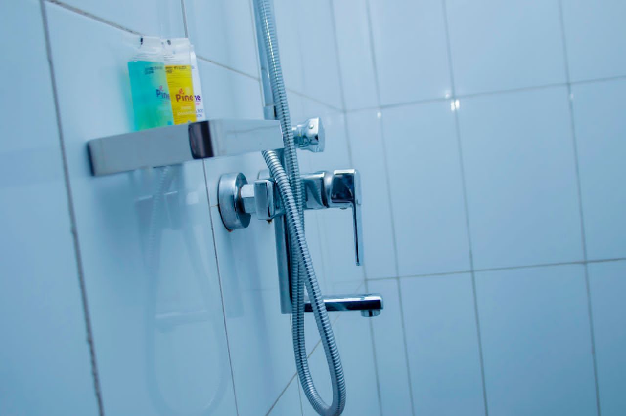 A shower with a handheld hose and a wall-mounted faucet.