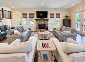 A spacious living room with a fireplace, multiple sofas, a coffee table, and a television. - NEW RENTAL! - The Eagle's Landing on Lake Martin (Jackson's Gap)