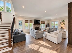 A spacious living room with a fireplace, multiple seating areas, and a staircase.
