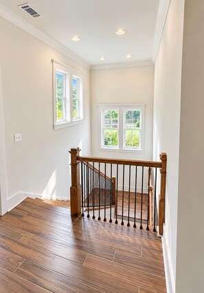 A staircase with wooden railings and a view of greenery outside. - NEW RENTAL! - The Eagle's Landing on Lake Martin (Jackson's Gap)