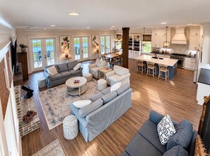 A spacious living area with a large sofa, a coffee table, and a dining table with chairs.