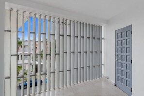 A room with a white door and a window with vertical blinds. - Maré 2BR | Near Ocean Park Beach + Laundry (San Juan)