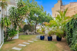 A garden with a paved path, potted plants, and outdoor furniture. - Maré 2BR | Near Ocean Park Beach + Laundry (San Juan)