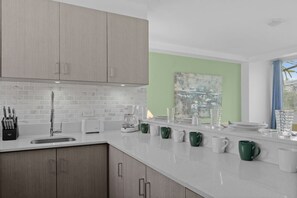 Eine moderne Küche mit weißer Arbeitsplatte, Spüle aus Edelstahl und Holzschränken.