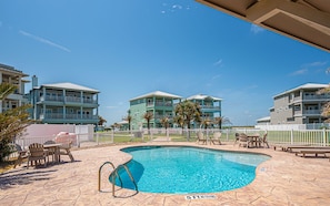 A swimming pool with a 5 ft no diving sign, surrounded by outdoor seating and a white fence. - Cici's Hideaway (Port Aransas)
