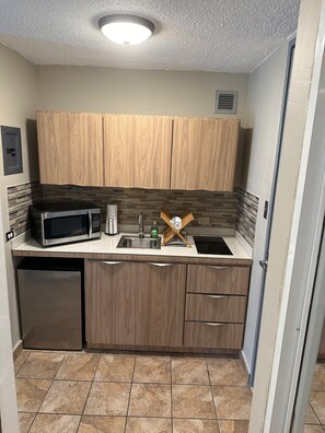 A compact kitchen with wooden cabinets, a microwave, a sink, and a dishwasher. - Saint Tropez Great Apartment & Location (Carolina)