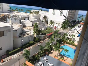 A rooftop pool area with a view of the ocean, palm trees, and adjacent buildings. - Saint Tropez Great Apartment & Location (Carolina)