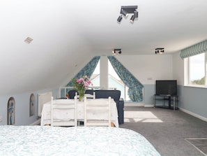 A bedroom with a bed, a desk, a chair, a TV, and a window. - Merlins Hideaway (Dawlish)