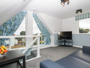 A room with a TV, seating, and a view of the outdoors. - Merlins Hideaway (Dawlish)