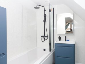 A modern bathroom with a glass-enclosed shower, a white sink, and a mirror above it. - Merlins Hideaway (Dawlish)