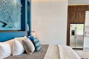 A modern hotel room with a bed, a wall art piece, and a refrigerator. - Pier 57 - Luxurious Condo in Zona Romantica (Puerto Vallarta)