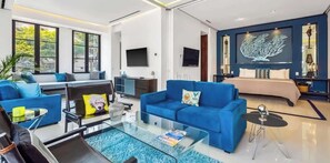 Ein modernes Wohnzimmer mit einem blauen Sofa, einem Glastisch und einem großen Fenster.