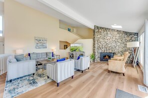 A spacious living area with a stone wall, a fireplace, and a staircase leading to an upper level. - Once Upon A Tide, by Vinifera Homes (Bodega Bay)