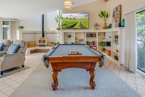 A living room with a pool table, a sofa, a fireplace, and a television. - Once Upon A Tide, by Vinifera Homes (Bodega Bay)