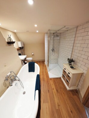 A modern bathroom with a freestanding bathtub, a glass-enclosed shower, and a white tiled shower wall. - Chinnerys Country Cottage (Sudbury)