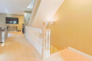 A spacious hallway with a wooden floor leading to a staircase with white balusters. - 4-storey Cedar Ridge townhouse - Hot tub - BBQ (Fernie)