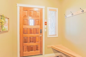 A wooden door with a window above it, a bench, and a wall-mounted shelf with hooks. - 4-storey Cedar Ridge townhouse - Hot tub - BBQ (Fernie)