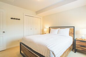 A bedroom with a bed, bedside tables, a wardrobe, and a door. - 4-storey Cedar Ridge townhouse - Hot tub - BBQ (Fernie)