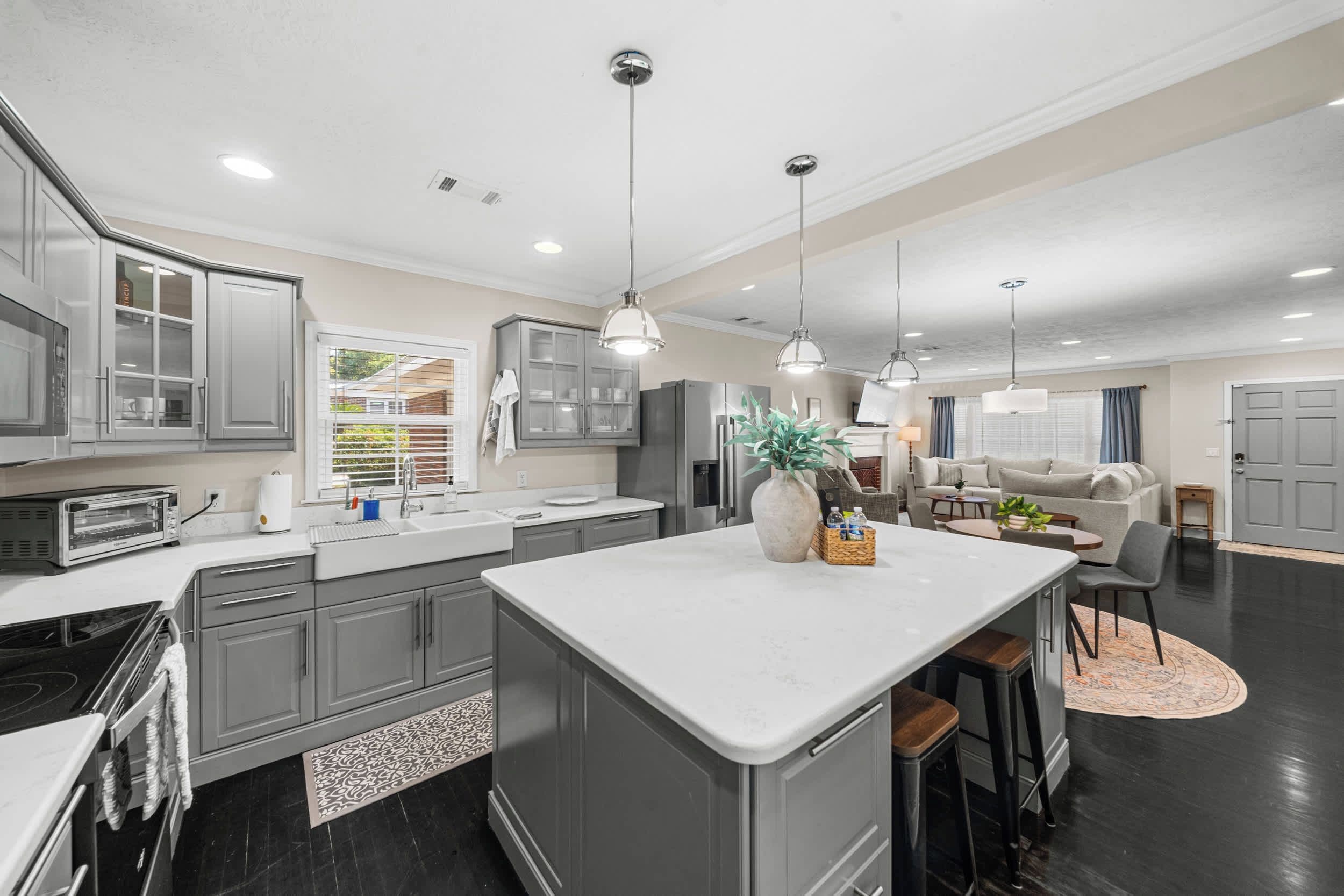 A modern kitchen with grey cabinets, a central island, and pendant lighting.