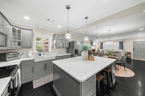 A modern kitchen with grey cabinets, a central island, and pendant lighting. - Get After that Azalea Walk to Georgia Southern (Statesboro)