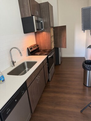 Una cocina moderna con electrodomésticos de acero inoxidable, lavavajillas y armarios de madera.