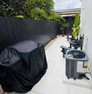 Ein überdachter Patio mit Tisch, einem Ventilator und einem Blumentopf.