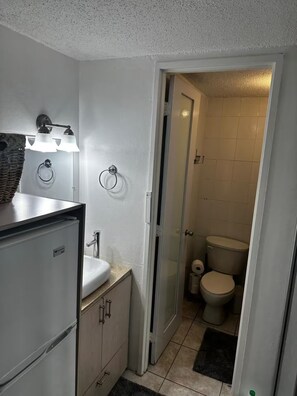 Et lille badeværelse med en hvid vask, et spejl og en håndklædering.