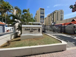 A sign for Saint Tropez with a beachside view, palm trees, and modern buildings in the background. - Relaxing Cozy Apartment (Carolina)