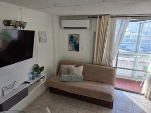 A living room with a flat-screen TV, a sofa, a potted plant, and a window with curtains. - Relaxing Cozy Apartment (Carolina)