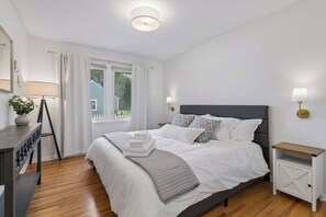 A neatly arranged bedroom with a bed, bedside tables, a lamp, and a window. - 4BR Chanhassen Home - 5-Min Walk to Dinner Theatre - Fire Pit (Chanhassen)