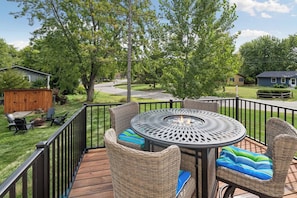 A deck with wicker furniture and a fire pit, overlooking a residential area with houses and trees. - 4BR Chanhassen Home - 5-Min Walk to Dinner Theatre - Fire Pit (Chanhassen)