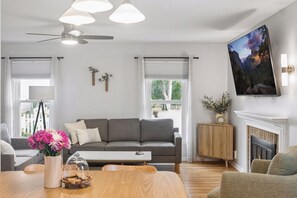Een moderne woonkamer met een grijze bank, een houten salontafel en een open haard.