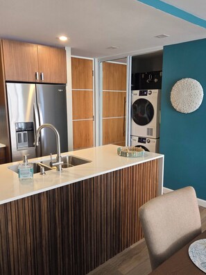 A compact kitchen with a built-in refrigerator, a sink, and a washing machine. - Spectacular Apt With Beach View (Carolina)