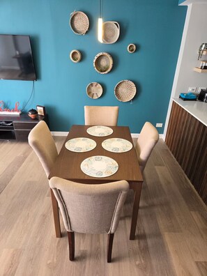 A dining area with a wooden table, four chairs, and decorative woven plates on the wall. - Spectacular Apt With Beach View (Carolina)