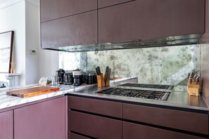 A modern kitchen with a stainless steel range hood, a marble countertop, and a variety of kitchen appliances. - Luxury 4-Bed House | Kensington, Notting Hill & Holland Park. (London)