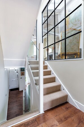 A staircase with carpeted steps leading to a landing with a glass door. - Luxury 4-Bed House | Kensington, Notting Hill & Holland Park. (London)