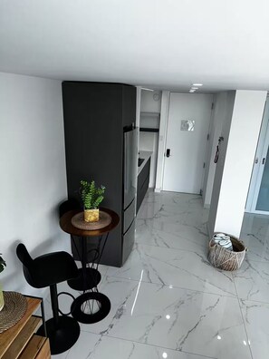A modern kitchen with a refrigerator, a dining area with a table and chairs, and a hallway leading to a bedroom. - Aqua Luxury Modern Beach Apartment (Carolina)
