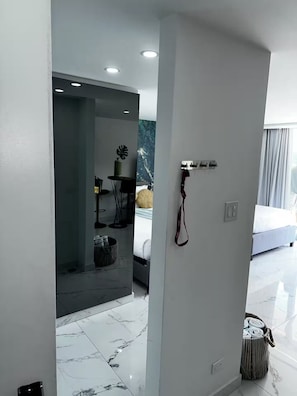 A modern hotel room with a marble floor, a bed, a small table with a chair, and a wall-mounted power outlet. - Aqua Luxury Modern Beach Apartment (Carolina)