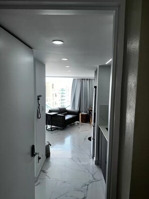 A modern interior with a marble floor, a sofa, and a view of buildings outside. - Aqua Luxury Modern Beach Apartment (Carolina)