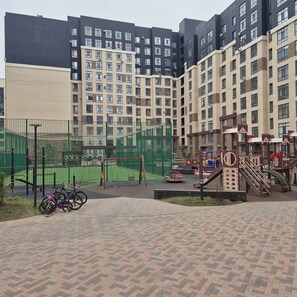 A playground area with a basketball court, swings, and climbing structures.