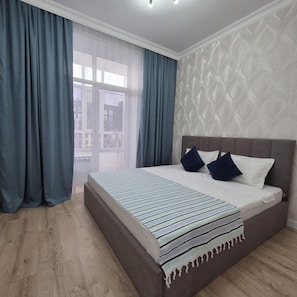 Ein Schlafzimmer mit einem großen Bett, einem Fenster mit Vorhängen und einer Wand mit Muster.