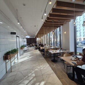 A modern restaurant with a long counter, seating area, and a view of the street.