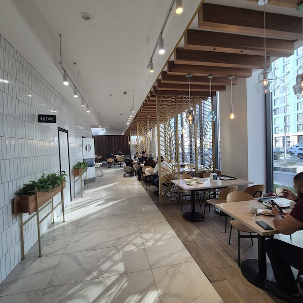 A modern restaurant with a long counter, seating area, and a view of the street.