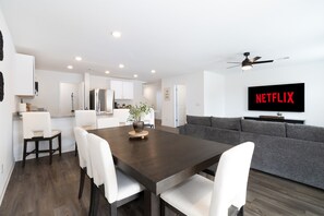 A modern living space with a dining area, kitchen, and a large flat-screen TV mounted on the wall. - Luxe Townhome near Lake Mohave & Laughlin (Bullhead City)