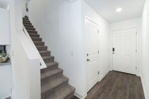 A staircase leading to a landing with a white wall and a door. - Luxe Townhome near Lake Mohave & Laughlin (Bullhead City)