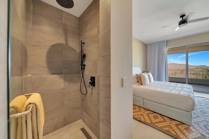 Ein modernes Hotelzimmer mit Dusche, einem Bett und einem großen Fenster mit Blick.