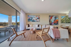 Uma sala de estar moderna com sofá, poltronas, mesa de centro e obras de arte nas paredes.